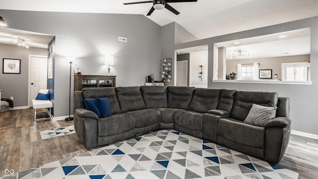 living room featuring light wood-style floors, ceiling fan, lofted ceiling, baseboards, and a chandelier
