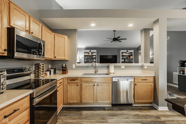 kitchen featuring stainless steel appliances, a sink, ceiling fan, dark wood finished floors, and light countertops
