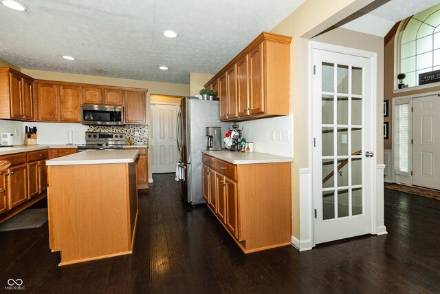 11727 Wedgeport Ln, Fishers, IN 46037 - kitchen with stainless steel appliances, light countertops, backsplash, a kitchen island, and dark wood finished floors