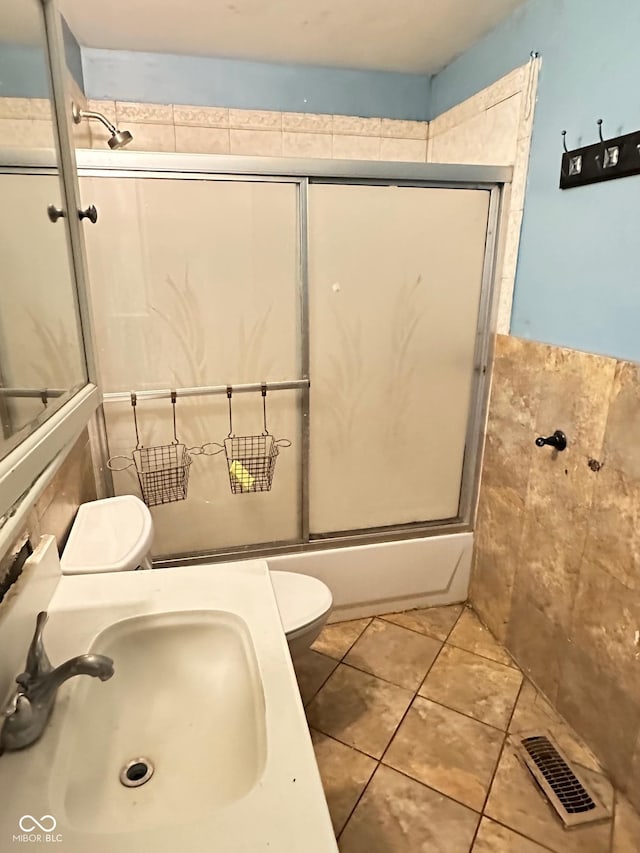 834 N Temple Ave, Indianapolis, IN 46201 - full bathroom featuring a sink, toilet, tile walls, tile patterned floors, and shower / bath combination with glass door