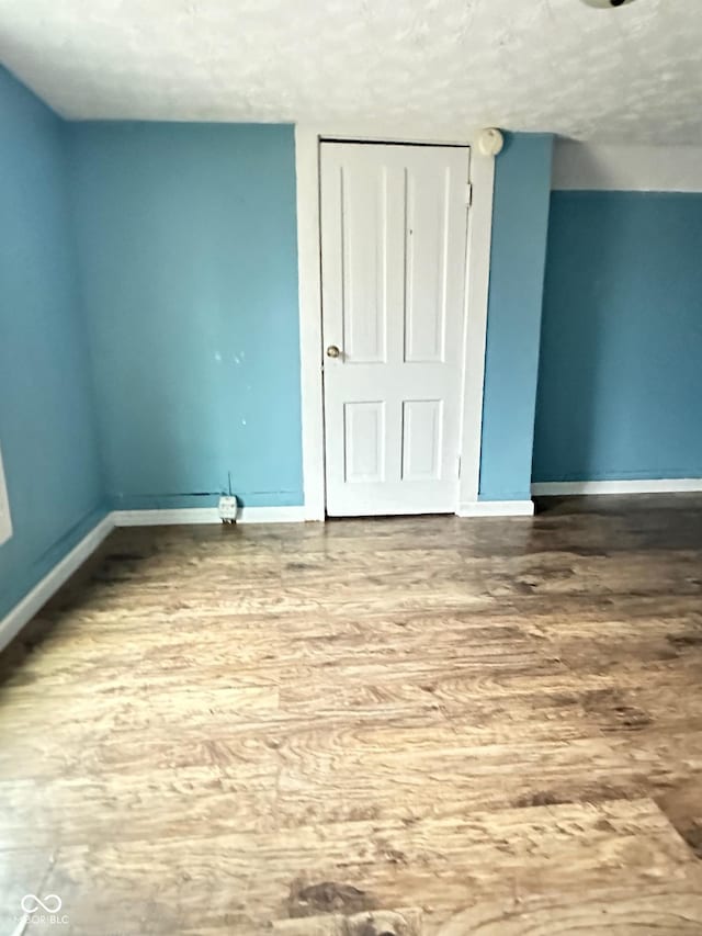 834 N Temple Ave, Indianapolis, IN 46201 - unfurnished bedroom featuring baseboards, wood finished floors, a textured ceiling, and a closet