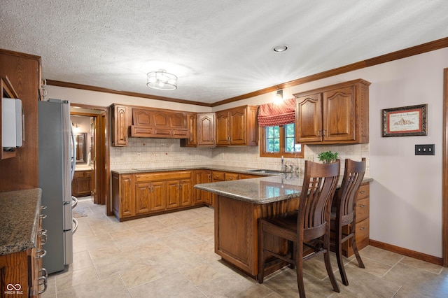 6575 Robin Hood Dr, Indianapolis, IN 46227 - kitchen with freestanding refrigerator, brown cabinets, a peninsula, a sink, and ornamental molding