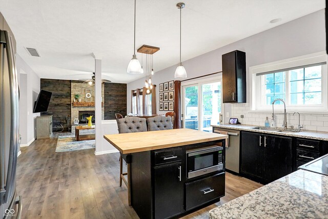 kitchen with dark cabinetry, wood counters, stainless steel appliances, light wood-type flooring, and a breakfast bar area