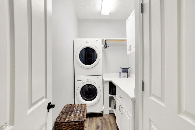 washroom with stacked washer and clothes dryer, dark wood finished floors, a textured ceiling, and cabinet space