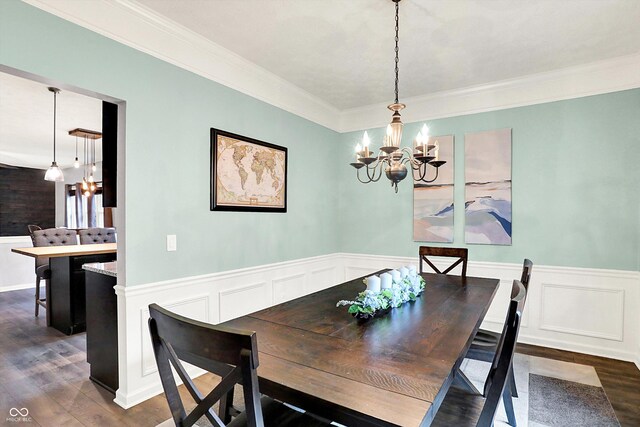dining space with a chandelier, dark wood-type flooring, crown molding, a wainscoted wall, and a decorative wall