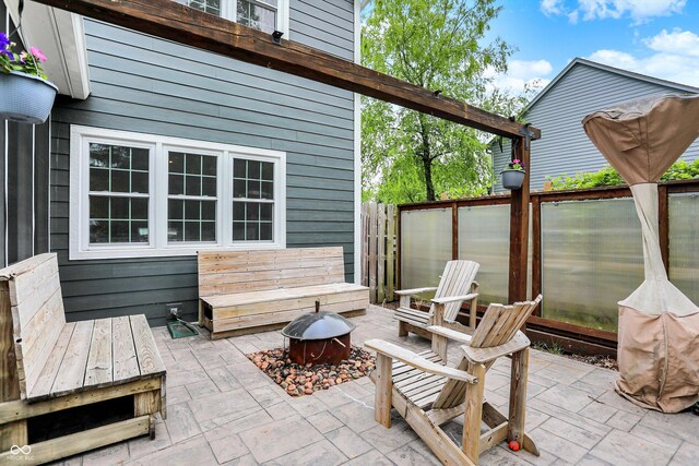 view of patio with fence and a fire pit