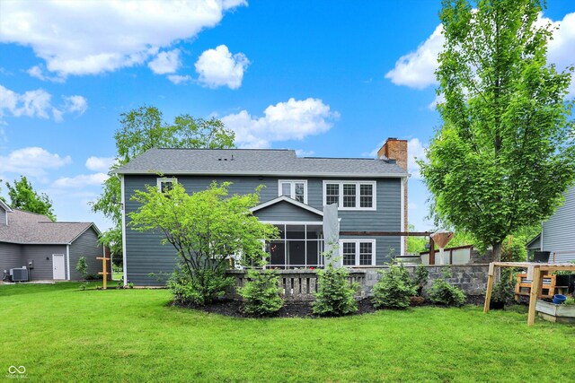 rear view of house with a chimney, cooling unit, a sunroom, and a shingled roof