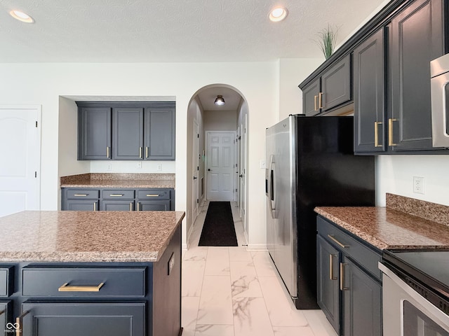 8644 N Deer Crossing Blvd, Mccordsville, IN 46055 - kitchen featuring light marble finish floors, arched walkways, recessed lighting, stainless steel appliances, and a textured ceiling