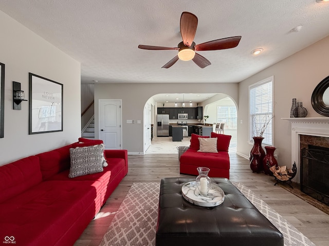 8644 N Deer Crossing Blvd, Mccordsville, IN 46055 - living area with arched walkways, a ceiling fan, stairs, a fireplace, and light wood finished floors