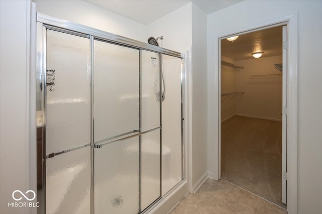 bathroom with a shower stall, baseboards, and a walk in closet