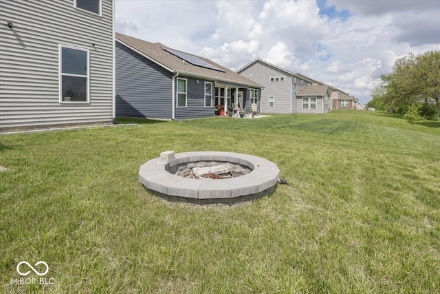 view of green lawn with an outdoor fire pit