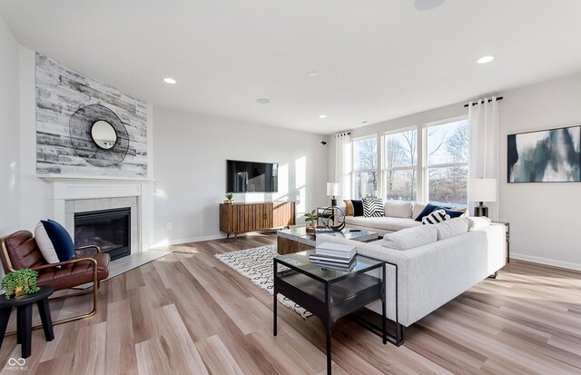 living area featuring light wood-type flooring, a tiled fireplace, baseboards, and recessed lighting