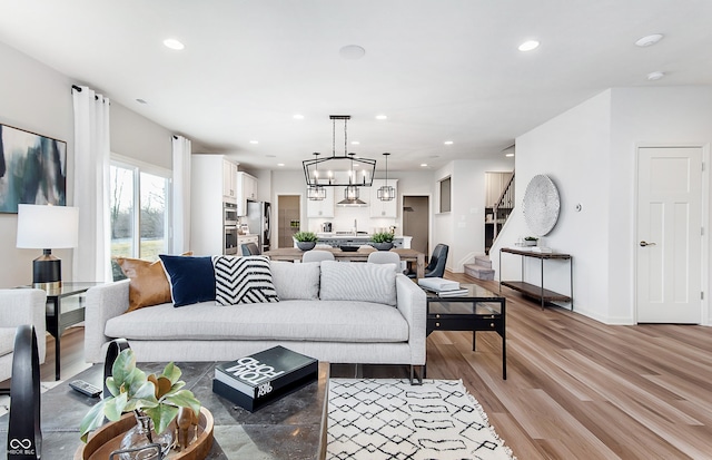 living room featuring light wood finished floors, recessed lighting, a chandelier, and baseboards