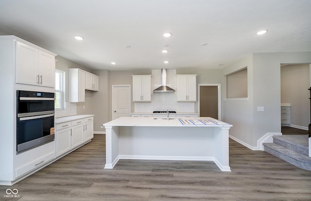 3256 Fawn Cir, Brownsburg, IN 46112 - kitchen featuring wall chimney exhaust hood, multiple ovens, decorative backsplash, white cabinetry, and recessed lighting