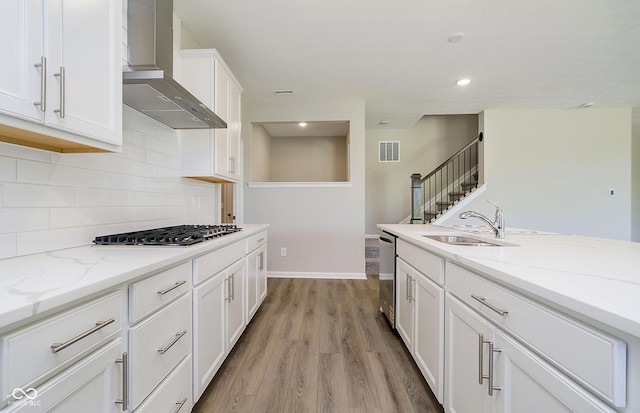 3256 Fawn Cir, Brownsburg, IN 46112 - kitchen with wall chimney range hood, white cabinetry, appliances with stainless steel finishes, light wood-style floors, and light stone counters