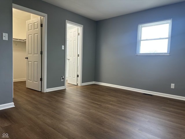 8417 S Sherman Dr, Indianapolis, IN 46237 - unfurnished bedroom featuring dark wood-style floors, a spacious closet, and baseboards