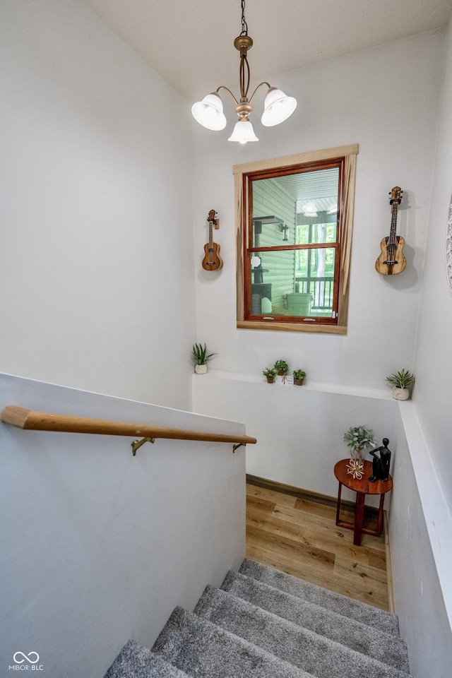 staircase with wood finished floors and a chandelier