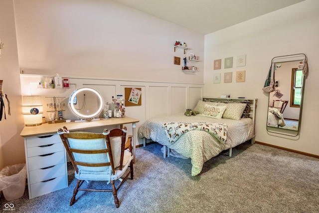 bedroom with carpet floors, a wainscoted wall, and a decorative wall
