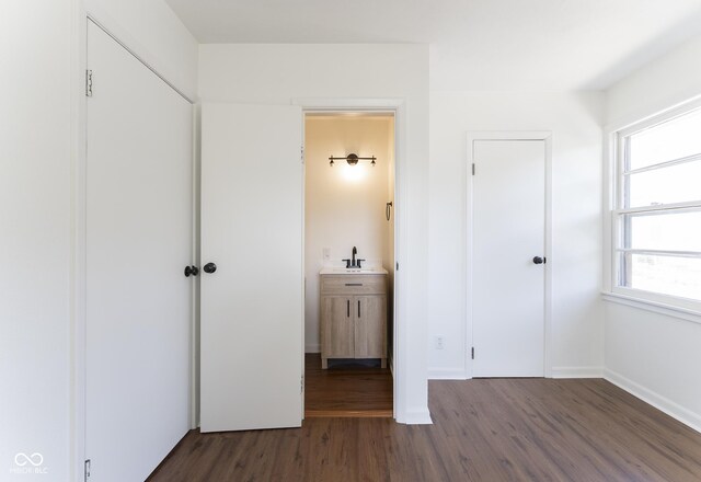 370 N Bazil Ave, Indianapolis, IN 46219 - unfurnished bedroom featuring a sink, wood finished floors, baseboards, and connected bathroom