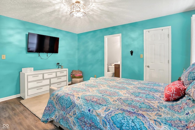 bedroom with wood finished floors, baseboards, a textured ceiling, and ensuite bathroom