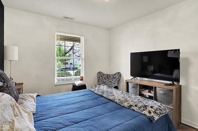 bedroom featuring wood finished floors, a textured ceiling, and baseboards