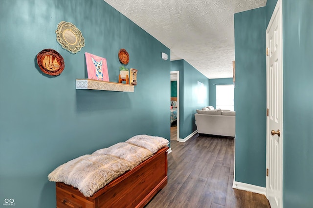 hall with a textured ceiling, baseboards, and dark wood-type flooring