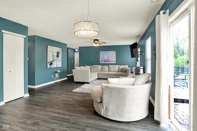 living room with dark wood-type flooring, baseboards, a chandelier, and ceiling fan