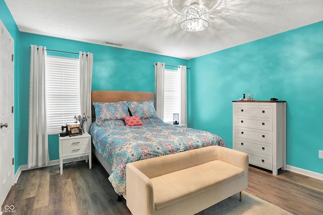 bedroom with wood finished floors, baseboards, and a textured ceiling