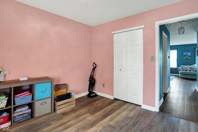 interior space with wood finished floors, a textured ceiling, and baseboards