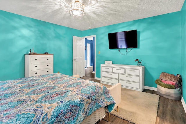 bedroom featuring wood finished floors, baseboards, and a textured ceiling