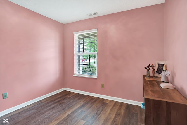 spare room with baseboards and dark wood finished floors
