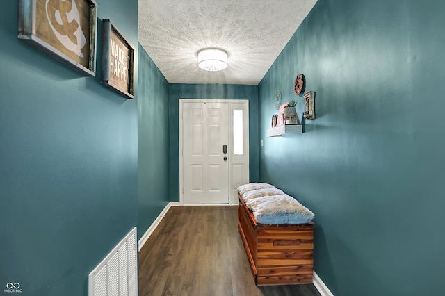 entryway with dark wood finished floors, baseboards, and a textured ceiling