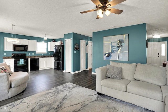 living room with dark wood-type flooring, a ceiling fan, a textured ceiling, and baseboards