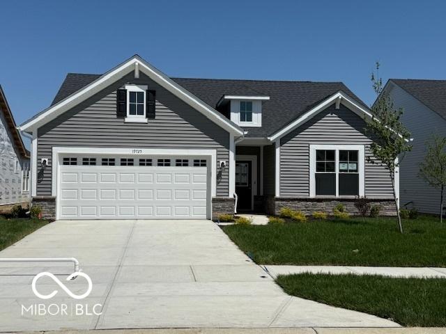 view of front of house with concrete driveway, stone siding, an attached garage, and a front yard