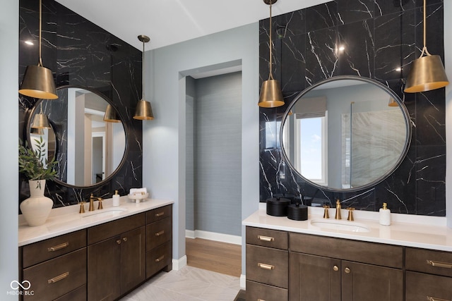 9602 Fall Creek Rd, Indianapolis, IN 46256 - bathroom featuring two vanities, baseboards, and marble finish floors