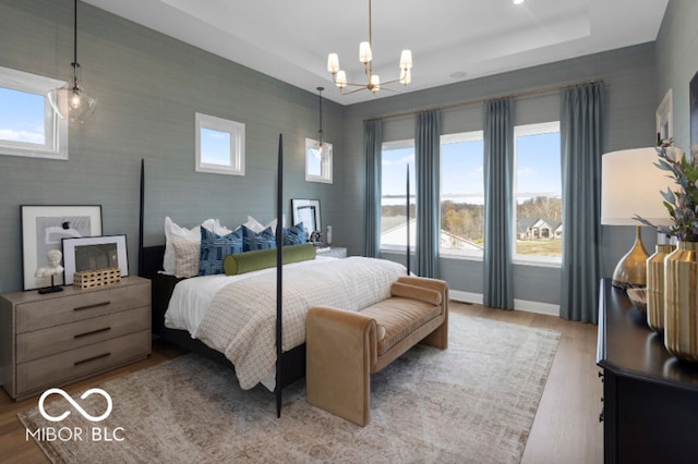 9602 Fall Creek Rd, Indianapolis, IN 46256 - bedroom with a raised ceiling, a chandelier, wood finished floors, and baseboards