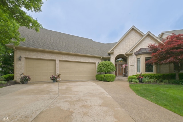 1614 Rosebud Ln Unit 83, Greenwood, IN 46143 - view of front of home with an attached garage, driveway, brick siding, and roof with shingles