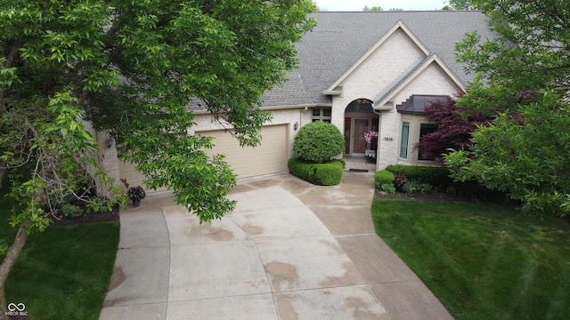 1614 Rosebud Ln Unit 83, Greenwood, IN 46143 - view of front of home featuring roof with shingles, concrete driveway, an attached garage, a front yard, and brick siding