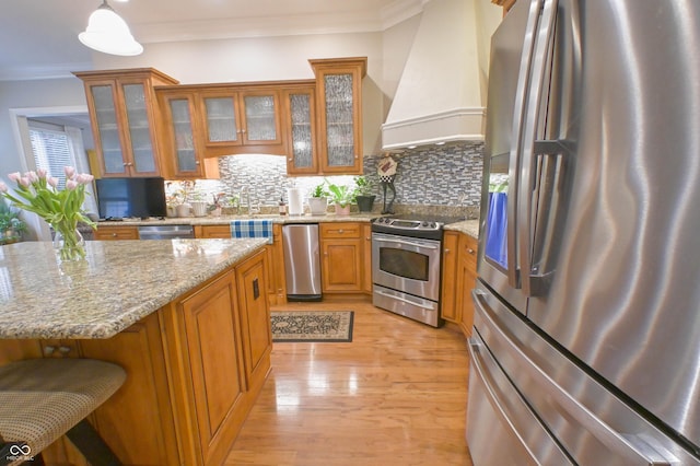 1614 Rosebud Ln Unit 83, Greenwood, IN 46143 - kitchen with stainless steel appliances, premium range hood, brown cabinetry, ornamental molding, and light wood-style flooring