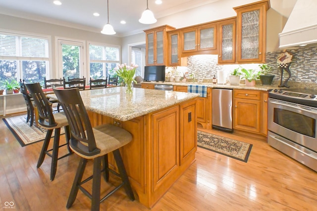 1614 Rosebud Ln Unit 83, Greenwood, IN 46143 - kitchen with appliances with stainless steel finishes, custom range hood, brown cabinets, a kitchen island, and a kitchen breakfast bar