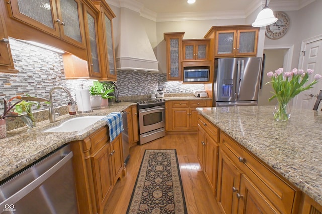 1614 Rosebud Ln Unit 83, Greenwood, IN 46143 - kitchen featuring appliances with stainless steel finishes, premium range hood, a sink, brown cabinets, and light wood-style flooring