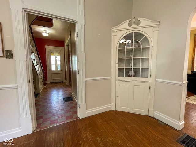 entrance foyer with arched walkways, baseboards, and wood finished floors