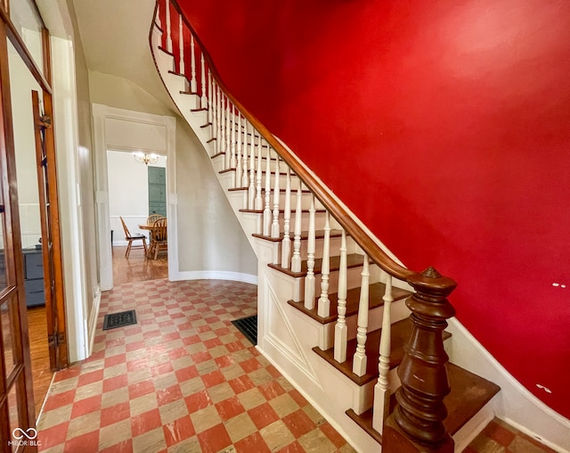 stairway featuring tile patterned floors, baseboards, and a chandelier