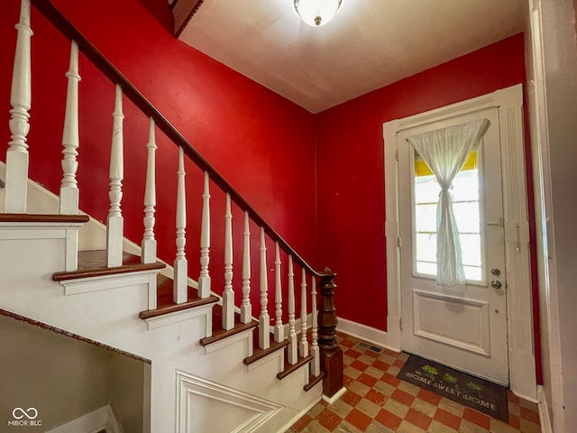 foyer featuring baseboards, stairs, and tile patterned floors