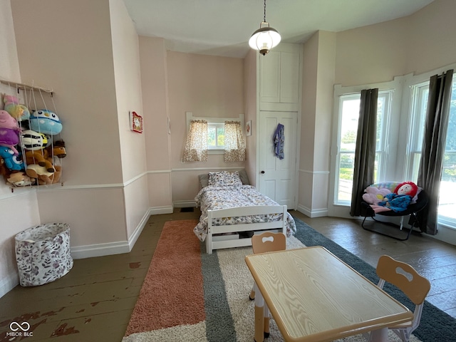 bedroom featuring multiple windows, baseboards, and wood finished floors