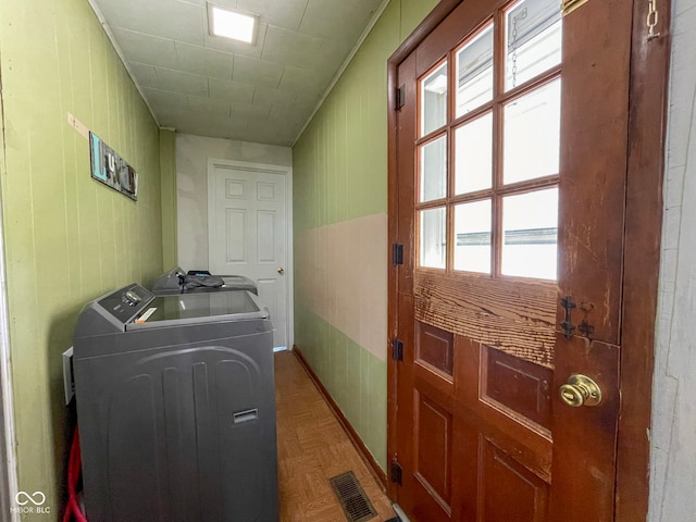 clothes washing area featuring separate washer and dryer, wood walls, and crown molding