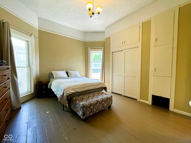 bedroom featuring dark wood-style flooring, a closet, a chandelier, and baseboards