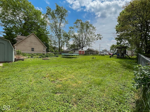 view of yard with a trampoline, a storage unit, a playground, and an outbuilding