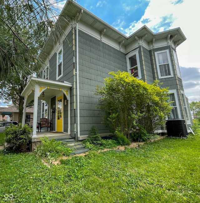 view of home's exterior with a porch, a lawn, and central AC