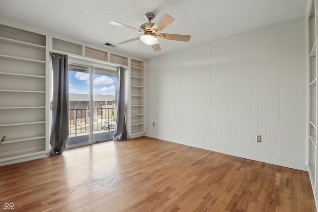 5038 Allisonville Rd Unit E, Indianapolis, IN 46205 - spare room featuring light wood-style flooring, a ceiling fan, built in shelves, a textured ceiling, and wood walls